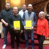 Gruppe der Absolventen und drei Prüfer*innen vor einer wunderschönen gedrechselten Holzstiege